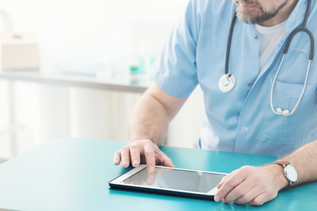 Doctor with stethoscope using tablet